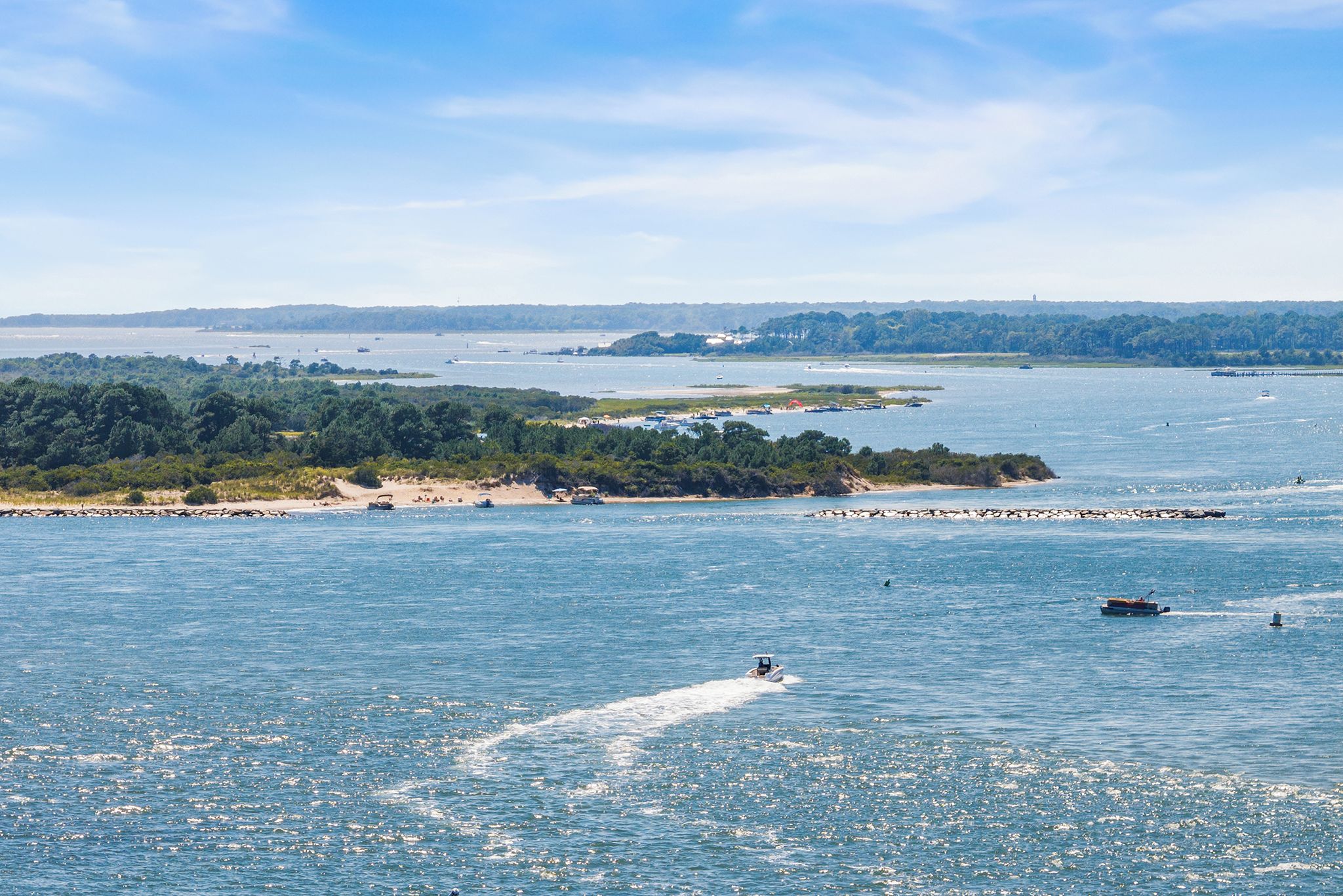 A coastal landscape with a sandy beach, a rocky outcrop, and a clear blue sky.