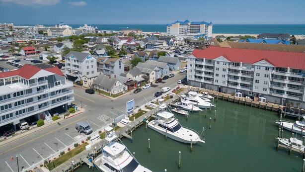 Un puerto deportivo con varias embarcaciones amarradas, rodeado de edificios residenciales y una carretera.
