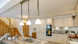 Eine moderne Küche mit Holzarbeitsplatte, Edelstahlspüle und Pendelleuchten.
