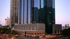 A high-rise building with a modern glass facade, surrounded by urban infrastructure.