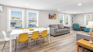 Een moderne woonkamer met een grijze bank, gele stoelen, een witte tafel en een grijze zithoek.