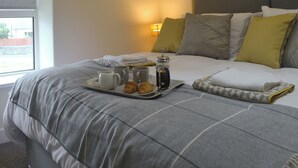 A neatly made bed with a tray of breakfast items, a bedside lamp, and a framed picture on the wall. - 2 bedroom accommodation in Bryncrug, near Tywyn (Bryncrug, near Tywyn)