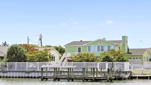 A waterfront property with a green house, dock, and white fence.