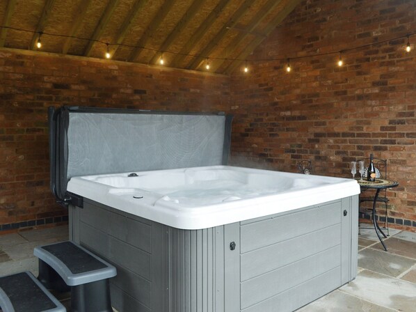 A hot tub in a brick-walled room with a wooden ceiling and string lights. - 2 bedroom accommodation in Ranby, near Retford (Ranby, near Retford)