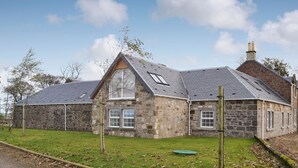 Une maison en pierre avec un toit en pente et de nombreuses fenêtres.