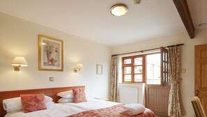 A hotel room with a large bed, two bedside lamps, a window with curtains, and a framed picture on the wall. - 2 bedroom accommodation in Sidbury, near Sidmouth (Sidbury, near Sidmouth)