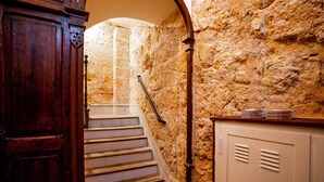 A stone-walled staircase with a wooden door and a metal railing.