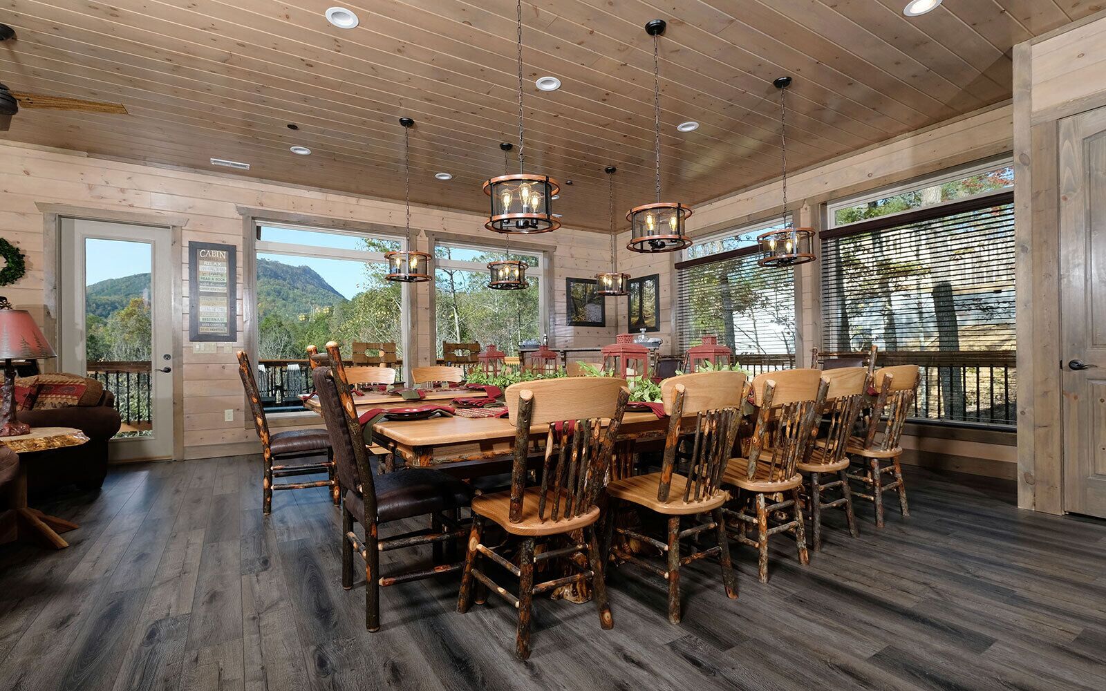 A rustic dining area with wooden tables and chairs, large windows, and a view of the outdoors.