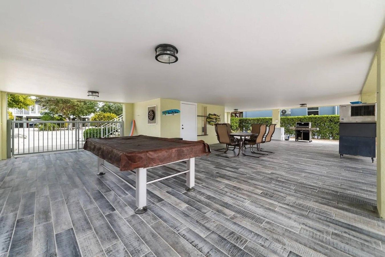 An outdoor patio with a pool table, dining area, and barbecue grill.