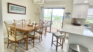 Une cuisine spacieuse avec un coin repas, comprenant une table et des chaises en bois, un luminaire suspendu et une vue sur l’extérieur.