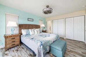 Ein Schlafzimmer mit einem Bett, Nachttischen, einer Bank, einem Deckenventilator und einem Kleiderschrank.