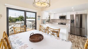 Una cocina moderna con electrodomésticos de acero inoxidable, un comedor con mesa y sillas, y un balcón con vistas.