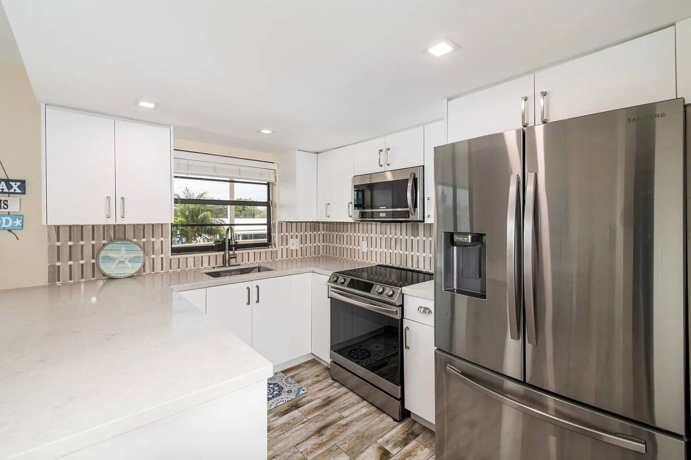 A modern kitchen with white cabinets, stainless steel appliances, a microwave, and a refrigerator.