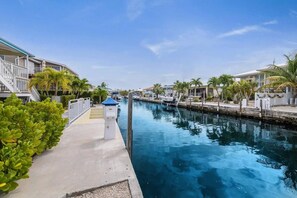 A marina with boats docked, a clear sky, and buildings with balconies. - Waterfront Home w/ Private Heated Pool & 60` Dock (Marathon)