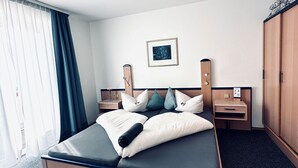 Una camera d'albergo con un letto, un comodino, un armadio e una luce a soffitto.