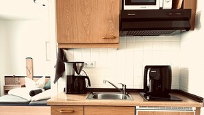 Una cucina compatta con mobili in legno, un forno a microonde, una macchina da caffè e un lavello.