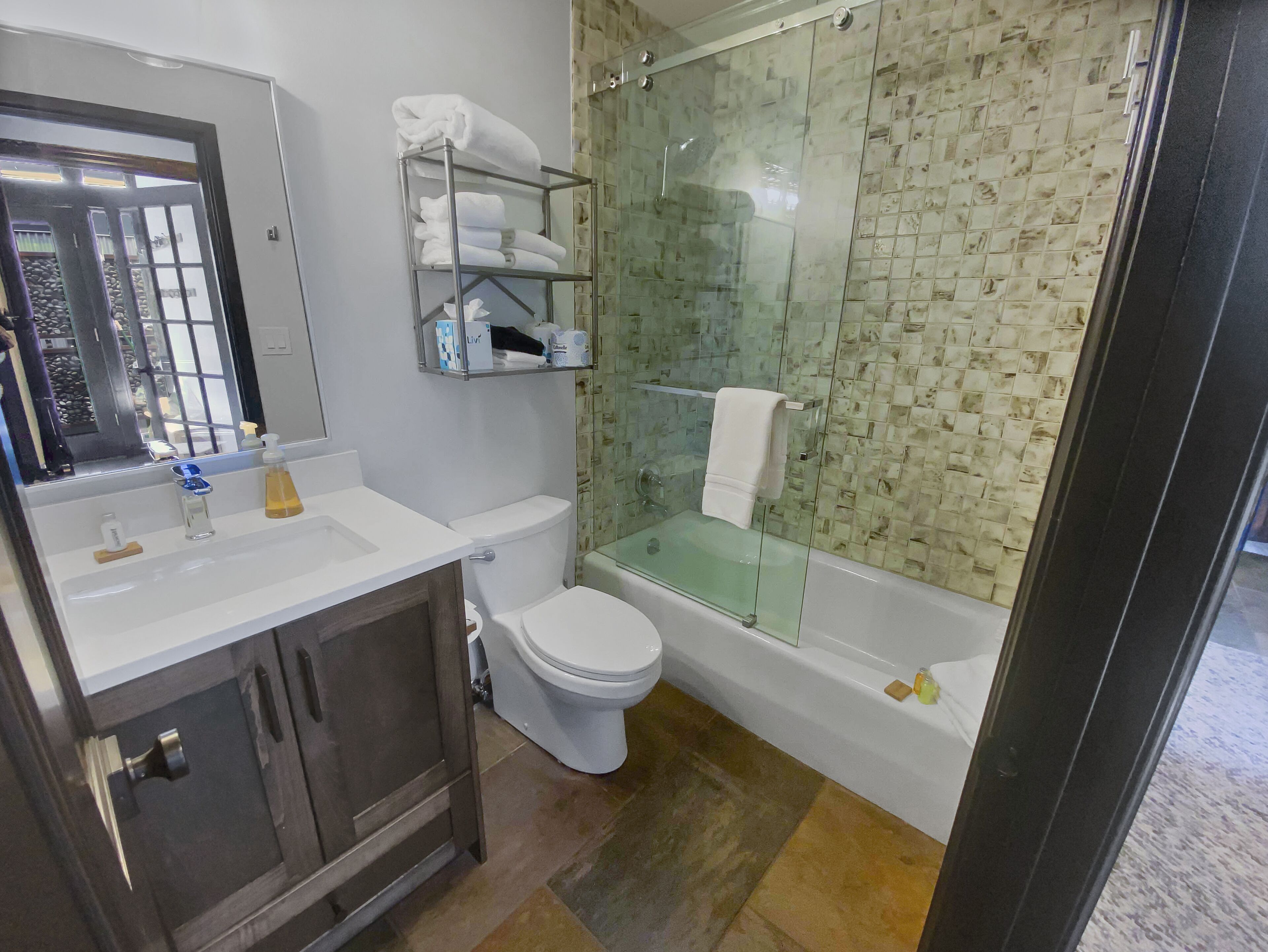 A modern bathroom with a glass-enclosed shower, a white toilet, and a vanity with a mirror.