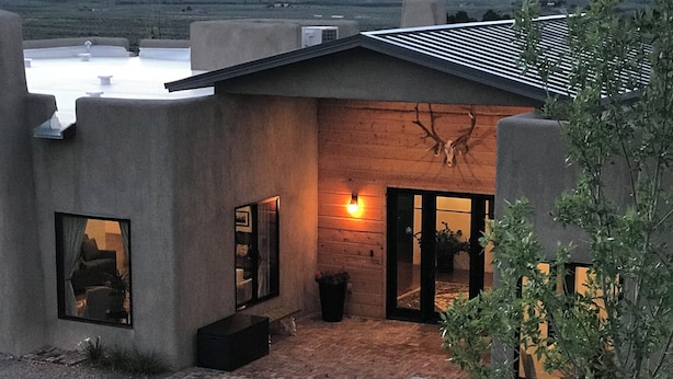 A modern house with a patio, a small garden, and a view of the landscape.