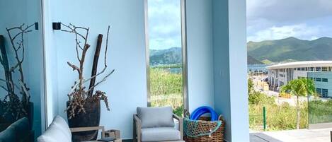 A balcony with a view of mountains and a building, furnished with a sofa, chairs, and a small table.