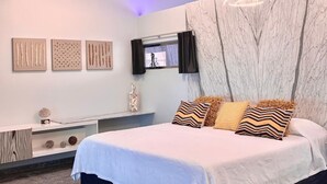 Une chambre à coucher moderne avec un lit, des œuvres d’art murales, un téléviseur et un mur d’accent en marbre.