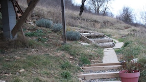 Un sendero que asciende una colina, con escalones y una estructura de madera a la izquierda.
