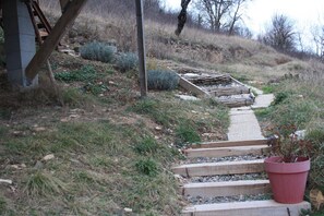 A pathway leading up a hill with steps and a wooden structure on the left.