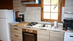Una cocina moderna con armarios de madera, horno empotrado, estufa a gas, un lavamanos y una ventana con vistas al exterior.