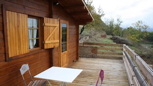 Una cabaña de madera con un porche, una mesa y dos sillas.