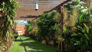 Un giardino con una pergola in legno, piante in vaso e un vialetto in pietra.