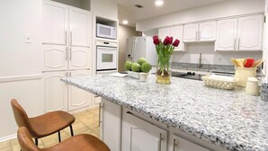 Eine moderne Küche mit weißen Schränken, Granit Arbeitsplatten, einer Mikrowelle und einer Vase mit roten Blumen.