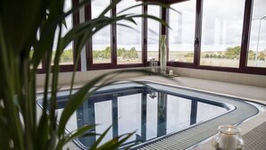 A modern indoor pool with clear glass walls, a view of the outdoors, and a candle on the poolside. - Chateau Vinasoro (Alcazar de San Juan)