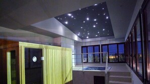 A modern interior with a starry ceiling, a hot tub, and a staircase leading to a balcony with a city view. - Chateau Vinasoro (Alcazar de San Juan)