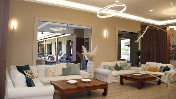 A modern living room with two white sofas, a wooden coffee table, and a large window offering a view of the interior. - Chateau Vinasoro (Alcazar de San Juan)