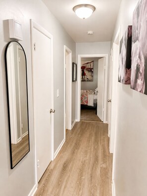 A hallway with a wooden floor, white walls, and doors leading to a bedroom. - ❤️ Unbeatable group travel retreat ❤️ (Omaha)