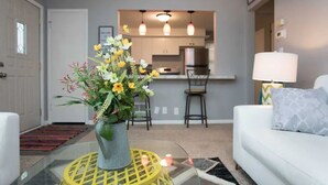 A living room with a white sofa, a yellow table, and a vase of flowers. - ❤️ Unbeatable group travel retreat ❤️ (Omaha)