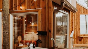 A wooden cabin with a stone sink, a mirror, and a window reflecting a cozy interior. - Perch small · Treehouse-Eagles Perch over the water (Port Angeles)