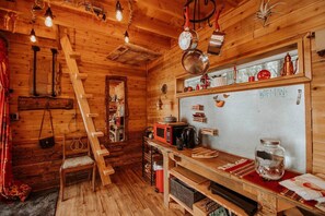 A rustic wooden cabin interior with a kitchen area, wooden shelves, and a ladder. - Perch small · Treehouse-Eagles Perch over the water (Port Angeles)