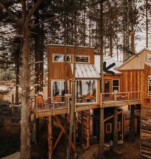 A wooden cabin with multiple levels, large windows, and a deck area. - Perch small · Treehouse-Eagles Perch over the water (Port Angeles)