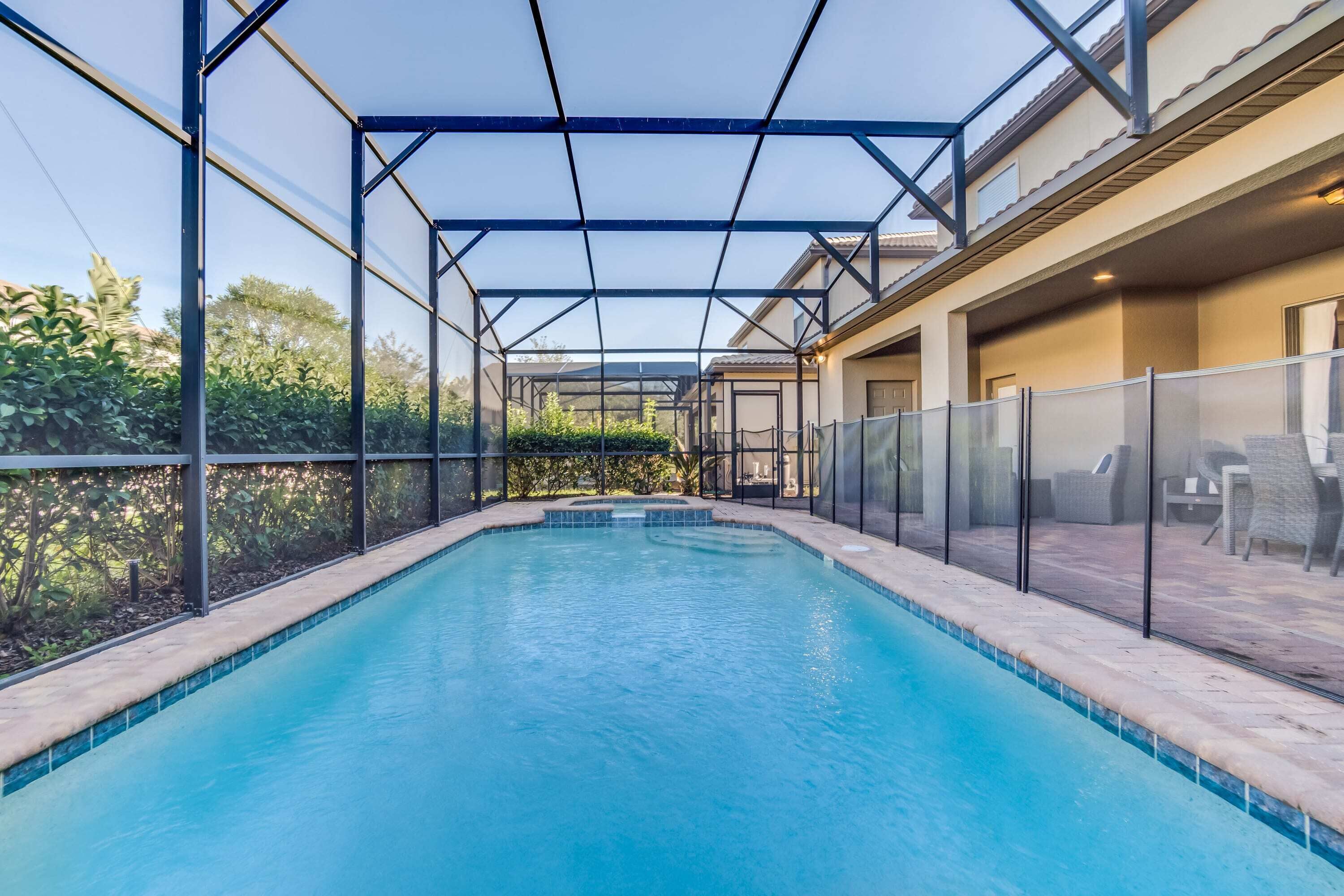 A swimming pool with a glass enclosure and a covered patio area.