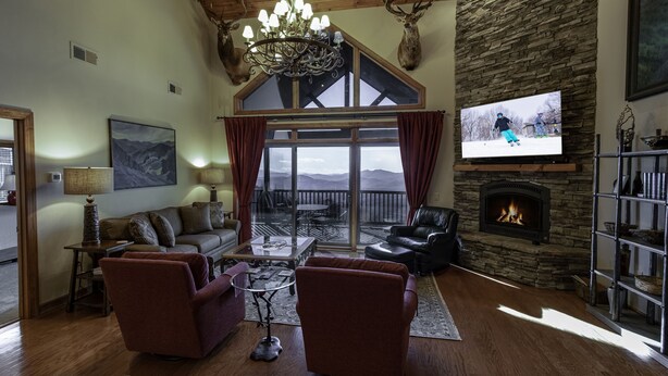 A cozy living room with a fireplace, a large TV, and a scenic view through the windows. - 'Elevation Station' at 5100 ft w/ Panormic Views (Sugar Mountain)