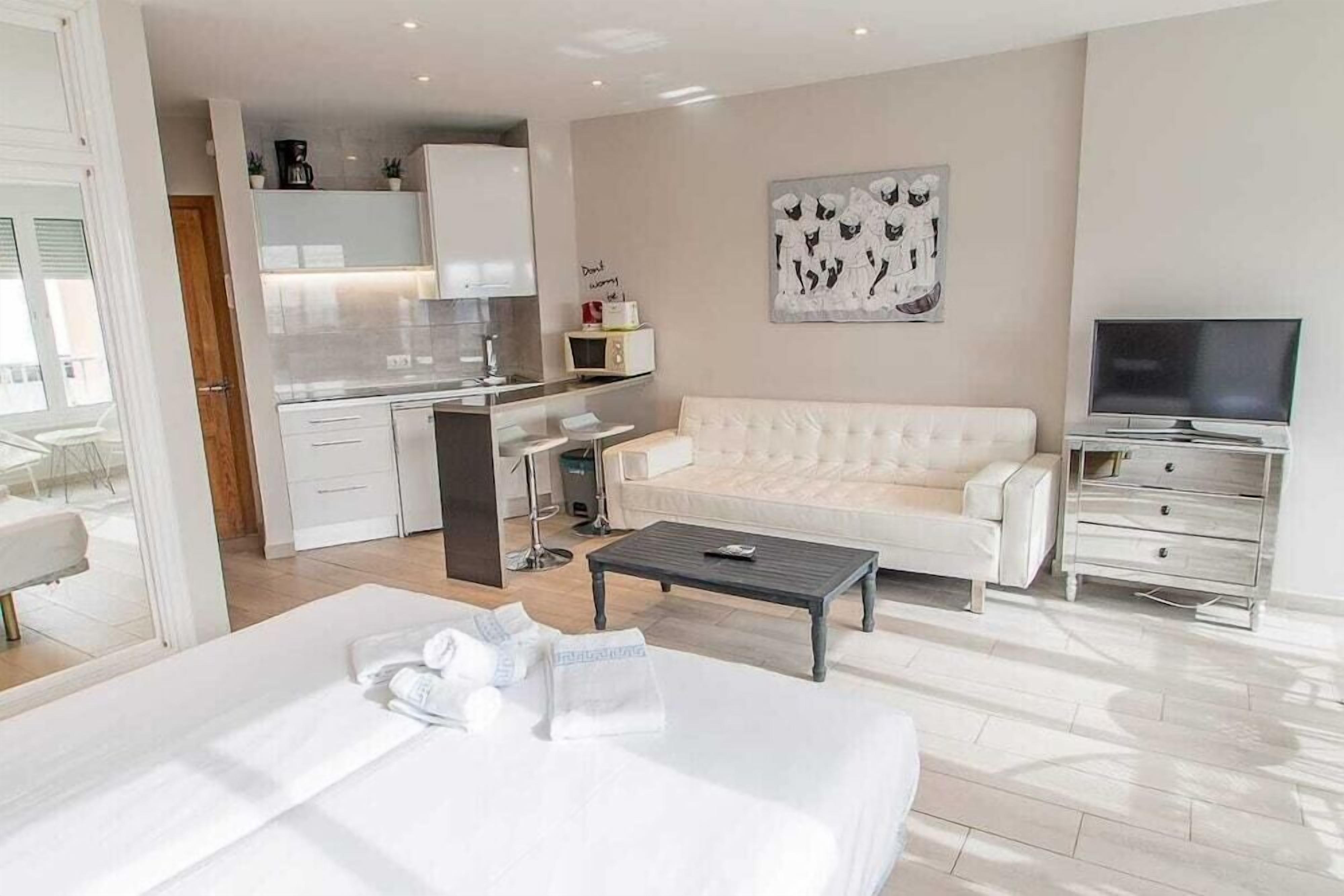 Una habitación de hotel con una cama, un sofá, un televisor, una mesa de centro y una kitchenette.