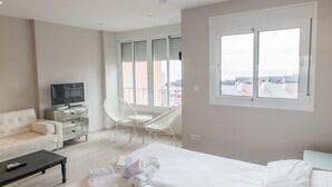 A modern hotel room with a bed, a television, a sofa, a dining table, and a chair. - Palm Beach Club (Torremolinos)