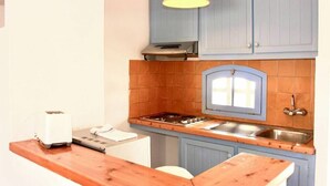 A kitchen with blue cabinets, a gas stove, a sink, and a toaster. - Apartamentos Posidonia (Mercadal)