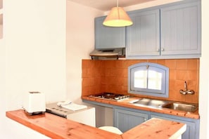 Una cocina con armarios azules, estufa a gas, lavamanos y tostadora.