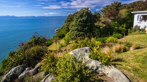 Une propriété située sur la côte, offrant une vue sur la mer, avec un grand arbre et une maison dotée d’un jardin.