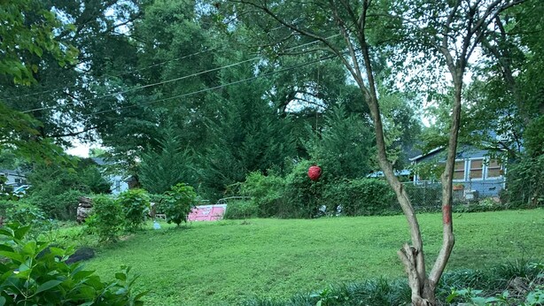 Un jardín con una estructura de madera hecha con tocones y una cuenca metálica.