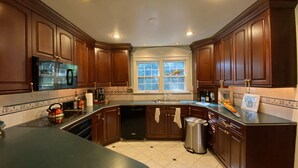 Una cocina con armarios de madera, un lavamanos de acero inoxidable y una ventana con vistas a árboles.