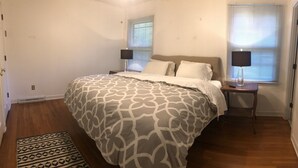 Un dormitorio con una cama grande, dos mesitas de noche y una alfombra estampada.