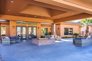 An outdoor patio area with seating, a fire pit, and a covered entrance.