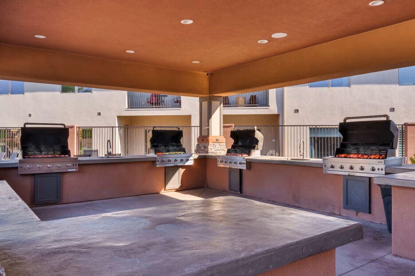 An outdoor kitchen area with multiple grills and a concrete countertop.